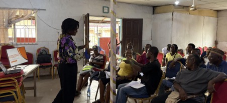 Community members in a hall being trained on waste management issues